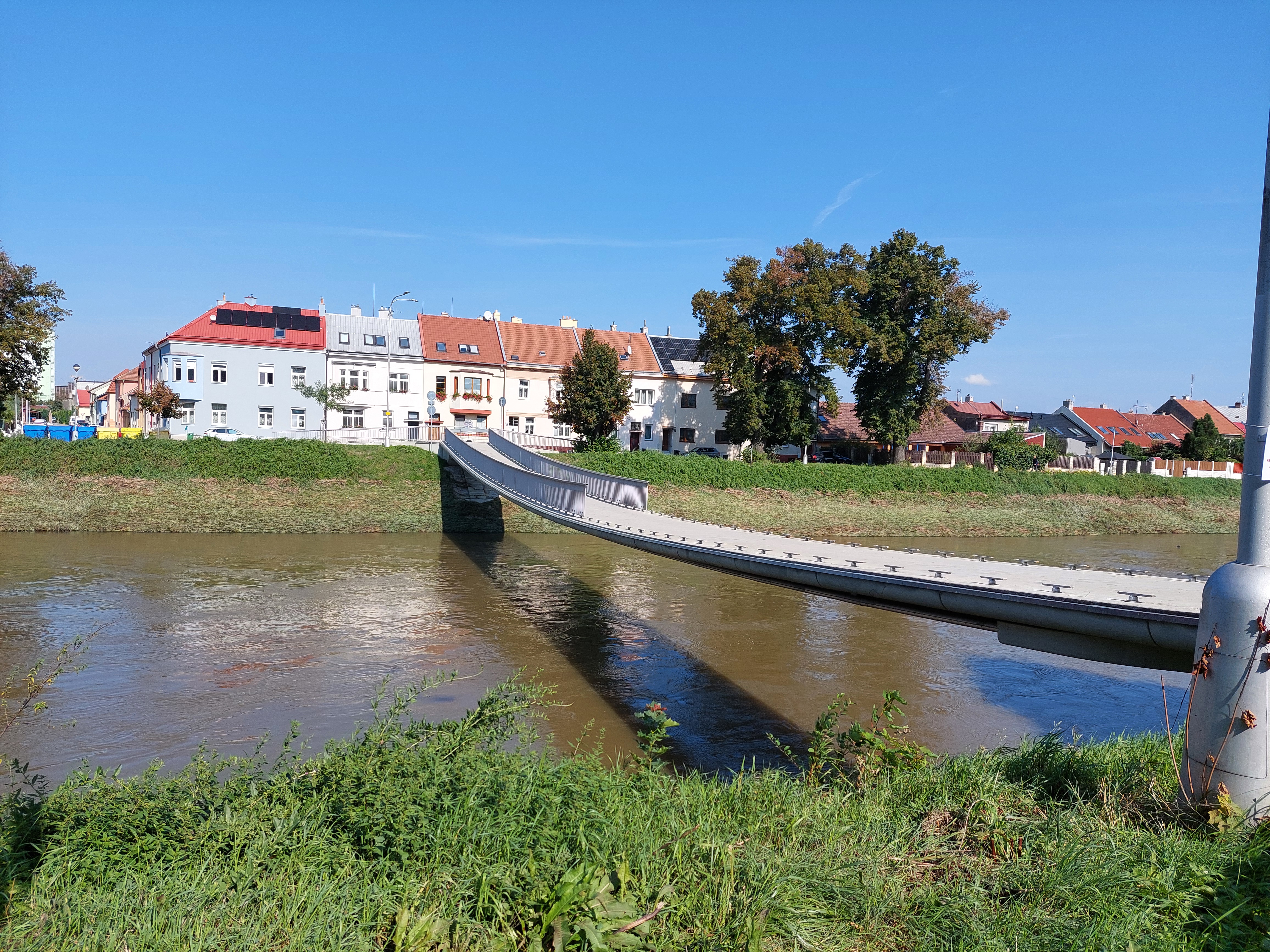 Pracovníci technických služeb postupně vracejí zábradlí na lávku pro pěší přes řeku Moravu.